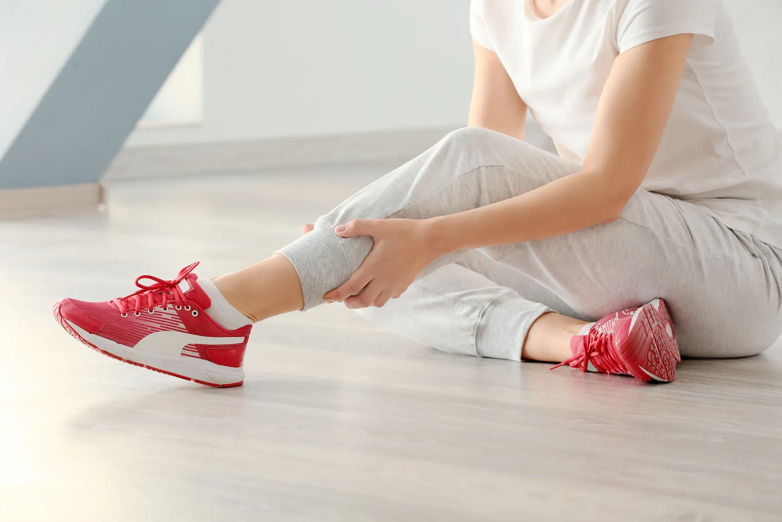 Runner clutching painful Achilles tendon at Spine-Ability Apollo Beach
